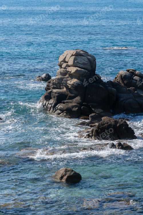 Preview: Wild rocky beach coastline and the sea, wave splashes on rock in sea shore, calm sea. Breaking waves