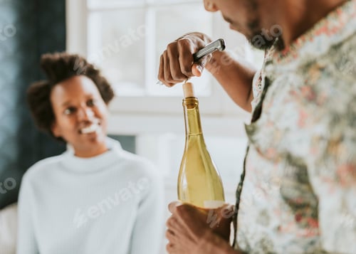 Preview: Happy black man uncorking a wine bottle