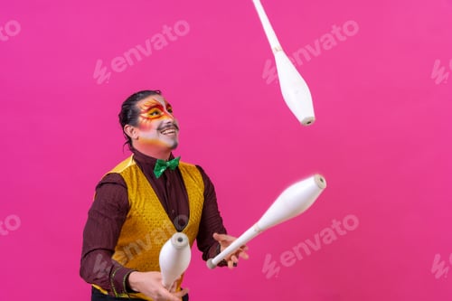 Preview: Clown with white facial makeup on a pink background, juggling maces