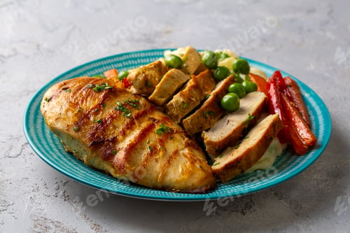 Preview: Grilled chicken breast slices served with mashed potatoes and vegetables.