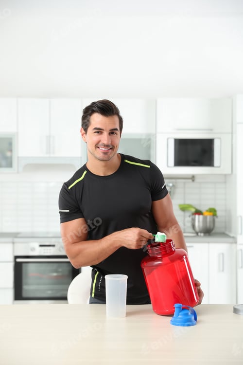 Preview: Young athletic man preparing protein shake in kitchen