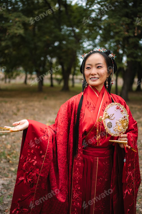 Preview: Smiling Chinese woman in traditional red dress holding fan