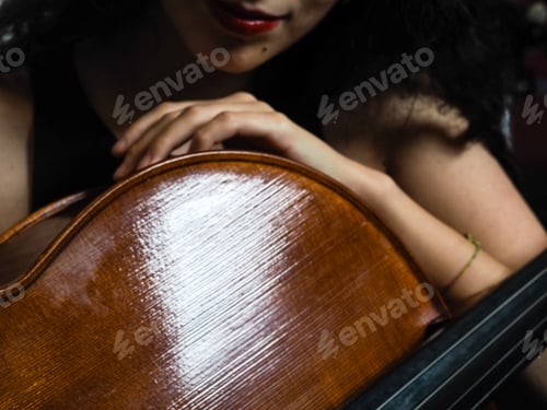 Preview: young female woman musician hold handmade classical cello in her hands over a solid background