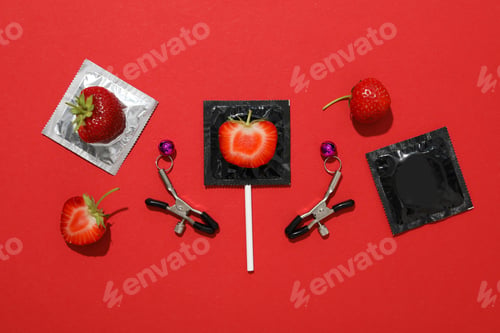 Preview: Condoms, strawberries and sex clothespins on a red background
