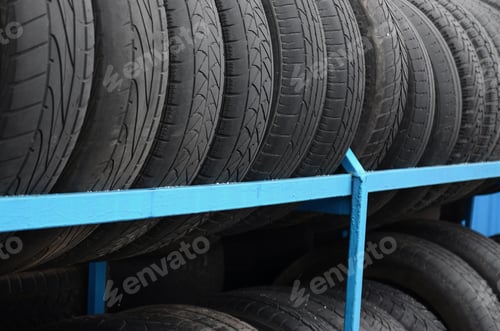 Preview: Rack with variety of car tires in automobile store. Many black tires. Tire stack background