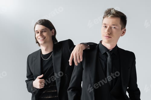 Preview: Positive gay standing near boyfriend in formal wear isolated on grey