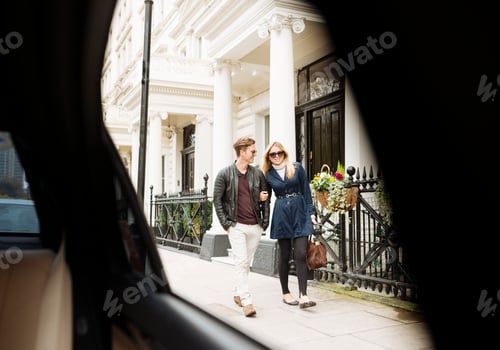 Preview: Car window view of young couple strolling on street, London, England, UK