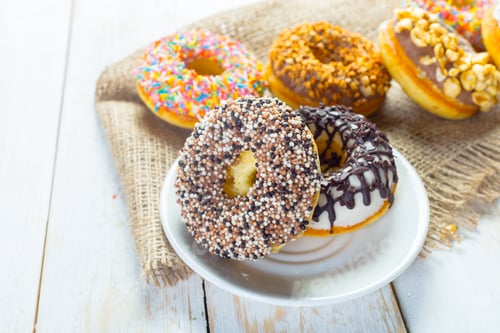 Preview: Delicious donuts with icing on plate on wooden background