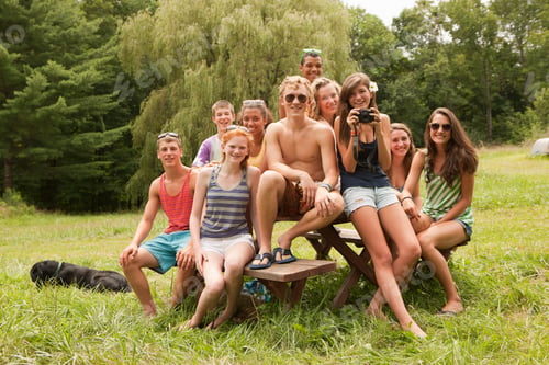 Preview: Teenagers relaxing together, sitting on a picnic table in the countryside