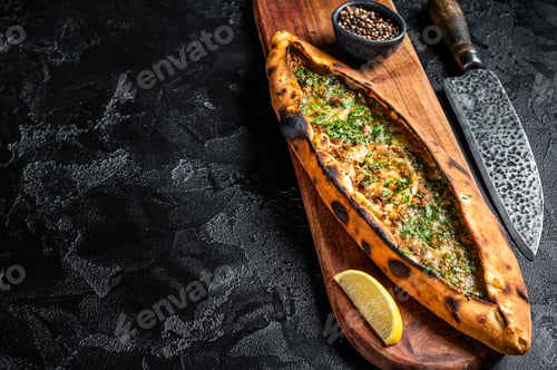 Preview: Turkish pide pie with beef meat and vegetables. Black background. Top view. Copy space