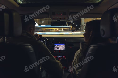Preview: Man and woman in a car at night, view from the car.