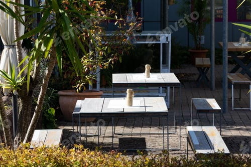 Preview: Several tables stand on a terrace decorated with flower pots and plants, waiting for guests