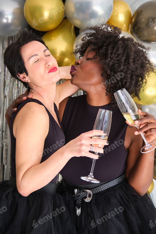 Preview: Two women with champagne glasses toasting and celebrating New Year in a party.