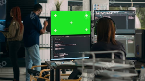 Preview: Software developer analyzing greenscreen and server code on multiple monitors