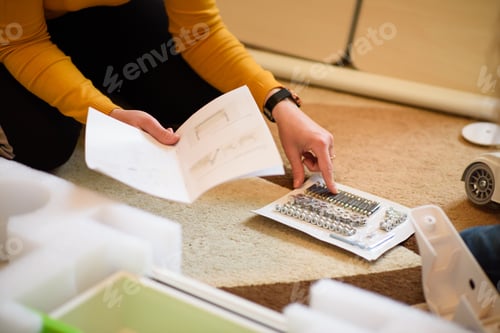 Preview: Woman studies the manual for assembling furniture and checks the availability of accessories