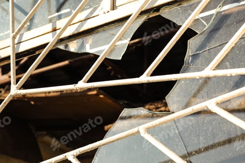 Preview: Broken window with metal grid outdoors. Requiring repair