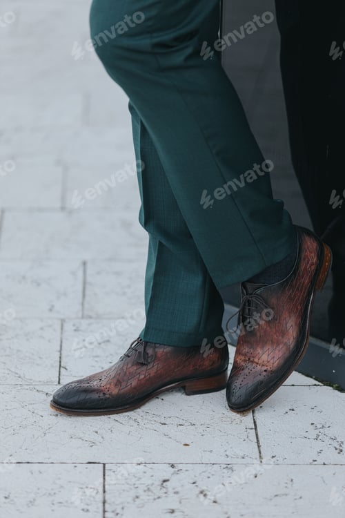 Preview: Vertical shot of a stylish man in dark gray suit pants and textured leather oxford shoes