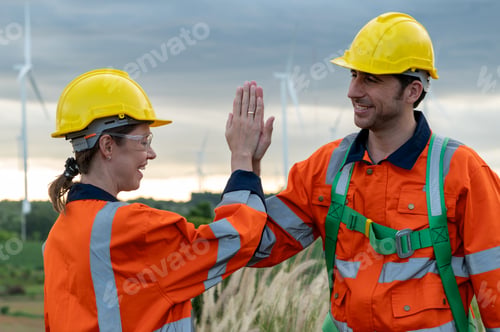 Preview: Smart engineers with protective helmet cheerfully giving high five at electrical turbines field