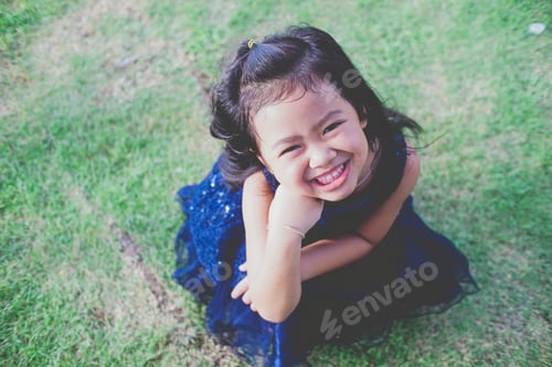 Preview: Smiling Girl in Blue Dress Sitting on Lawn