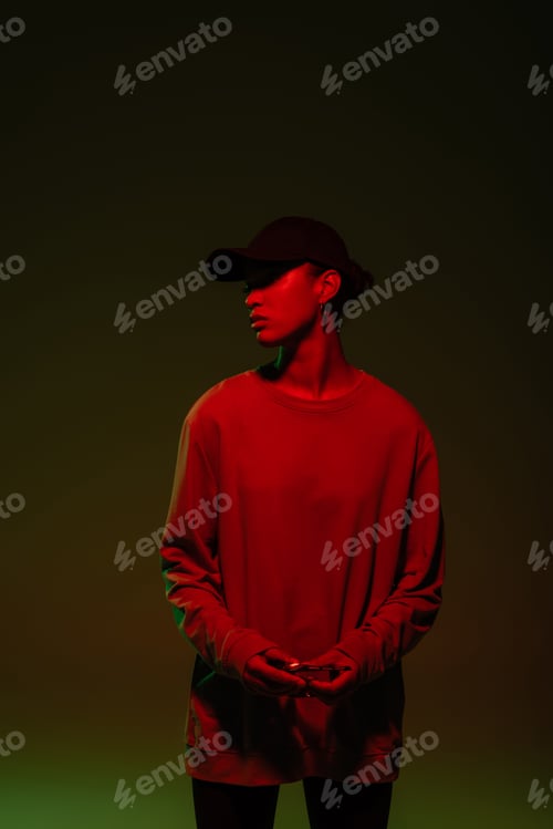 Preview: young african american woman in baseball cap and sweatshirt standing on green with red light