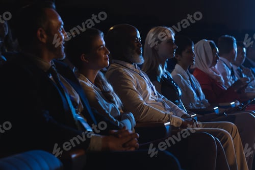Preview: Side view of mixed race business colleagues sitting and watching presentation with audience