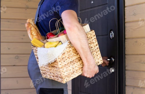 Preview: Fresh organic food in a wicker basket in the hands of a bicycle courier. Bike delivery or donation