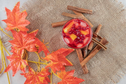 Preview: Glass of juice with fruit slices and cinnamon sticks on burlap