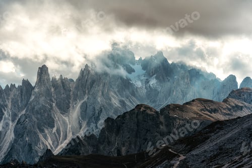 Preview: Alpine landscape of rugged Tre Cime mountain peak with misty in Dolomites, Italy