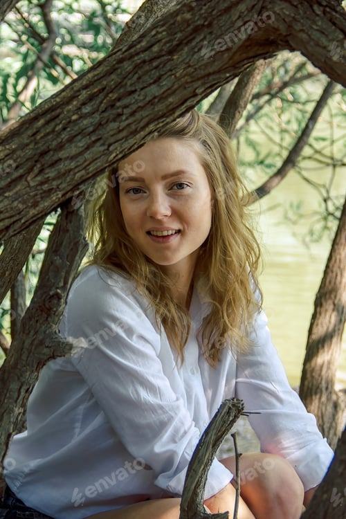 Preview: Portrait of a young Caucasian woman in summer in a park near trees near a lake. The girl is slender