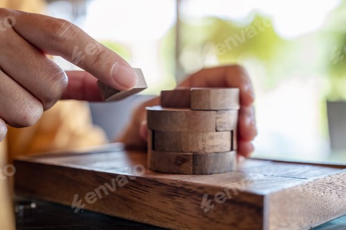 Preview: Closeup image of people playing and building round wooden puzzle game