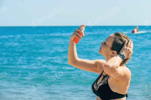 Preview: beautiful girl on the beach uses sunscreen
