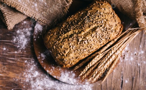 Preview: Top view of homemade bread loaf with wholegrain wheat on vintage wooden table.