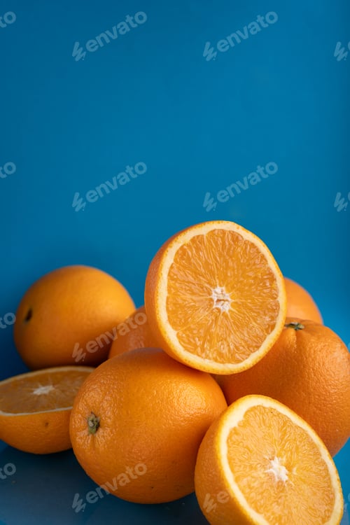 Preview: Halved and whole oranges on bright blue, highlighting rich textures and fresh appeal.