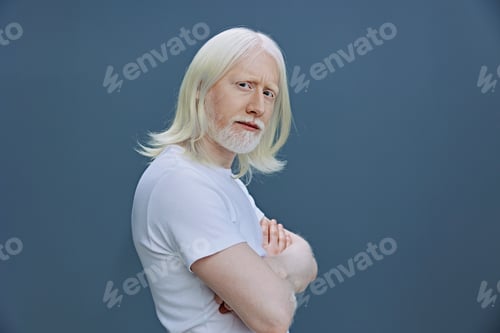 Preview: elderly man with long white hair and beard displays self confidence against a muted blue background