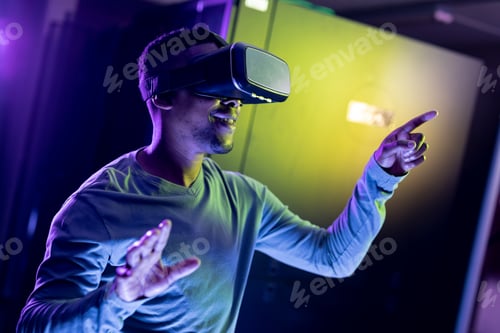 Preview: African american male computer technician wearing vr headset and working in server room