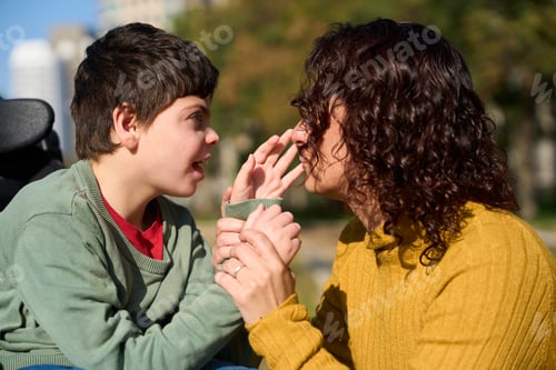 Preview: Loving mother interacting with son with disability in wheelchair in park