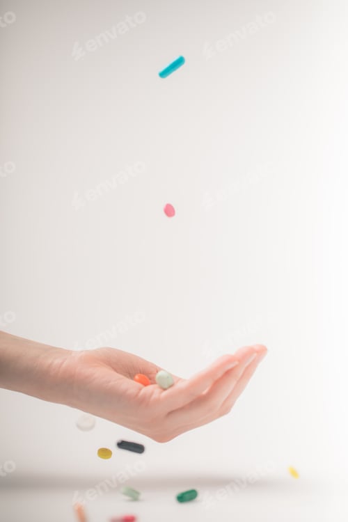 Preview: Cropped image of female hand catching falling pills