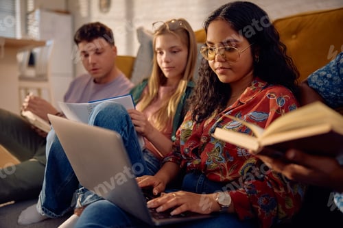 Preview: Young Indian student using laptop while learning with friends at home.