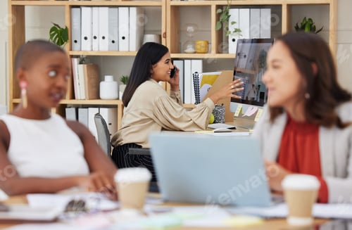 Preview: Serious ambitious indian business woman using cellphone to talk to clients while using office compu