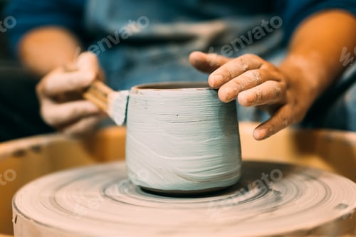 Preview: Craftsman potter making jug of clay on potter wheel circle in workshop