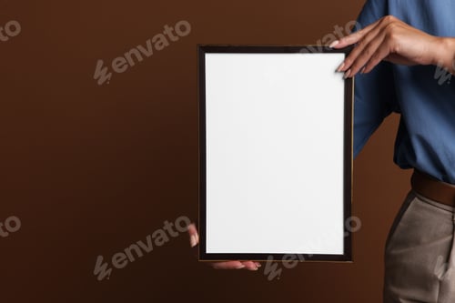 Preview: Woman with blank diploma frame on brown background, closeup. Mockup for design