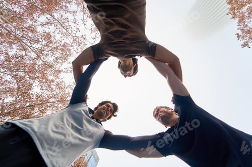 Preview: Team of athletes holding each other in a circle outdoors