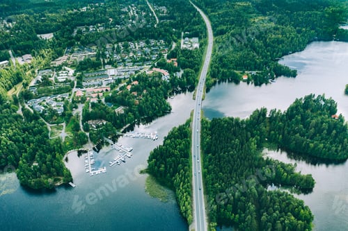 Preview: Aerial view of road bridge with cars between green forests and blue lakes in rural Finland