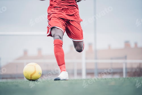 Preview: African soccer player with red outfit playing soccer.