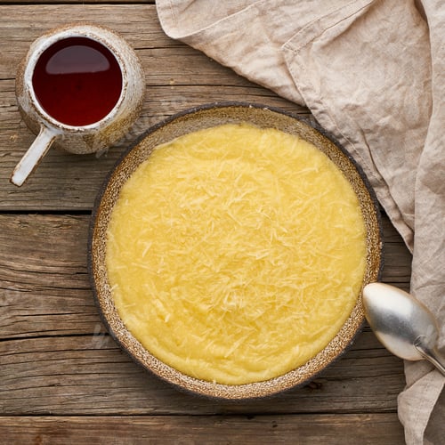 Preview: porridge polenta with cup tea, dark wood background, top view