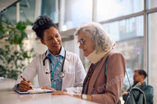 Preview: Smiling black doctor talking to senior woman with neck injury after medical examination.