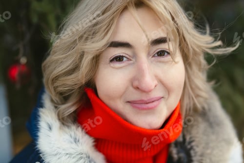 Preview: Portrait of a woman in a hood and a red scarf on a frosty day.