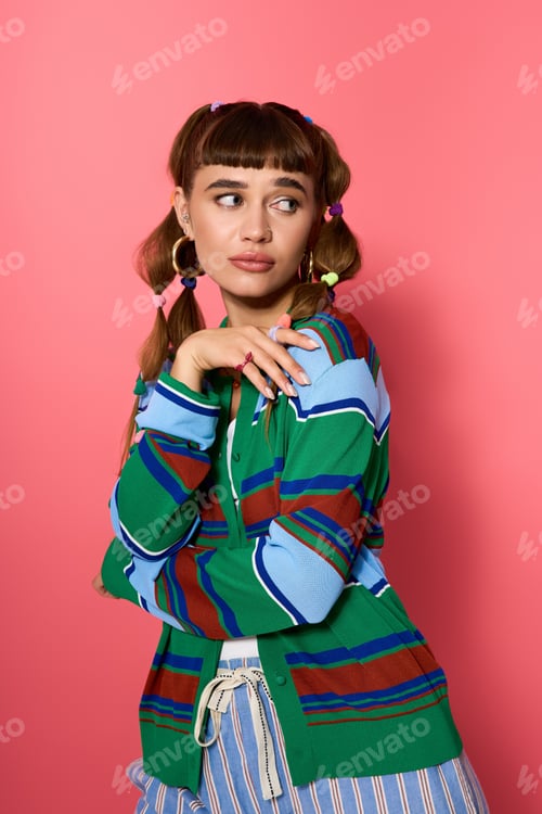 Preview: Young woman showcasing stylish fashion against a vibrant pink background in an energetic pose