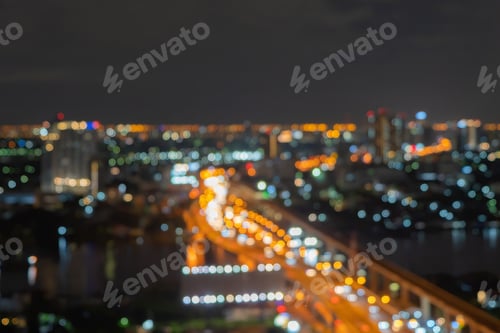 Preview: Bokeh of skyscraper buildings in city with lights, Blurry photo at night time. Cityscape background