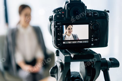 Preview: selective focus of digital camera shooting smiling journalist in office
